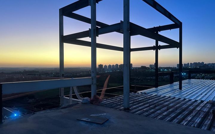 Pórtico metálico no fim da tarde, com a cidade no horizonte